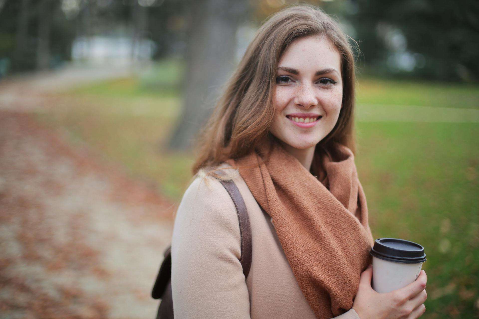 Leende ung kvinna som håller en kaffekopp, symbol för balans och karriärinspiration.