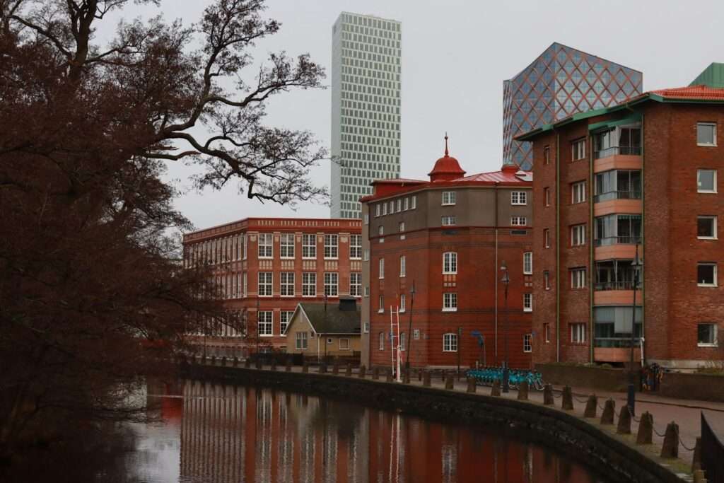 Stadsbild med röda tegelbyggnader vid en kanal, symboliserar modern arbetsmiljö och stadsliv.